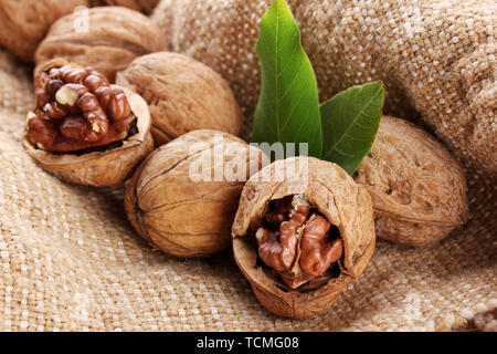 walnuts with green leaves, on burlap background Stock Photo
