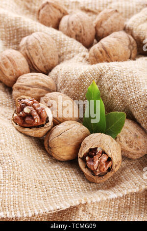 walnuts with green leaves, on burlap background Stock Photo