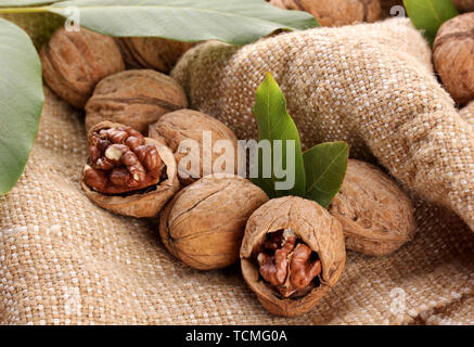 walnuts with green leaves, on burlap background Stock Photo