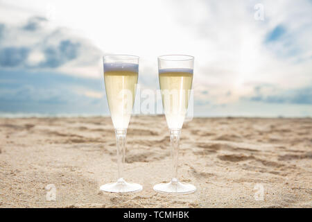 Two Glasses Of Champagne On Sandy Beach Against Blue Sky Stock Photo