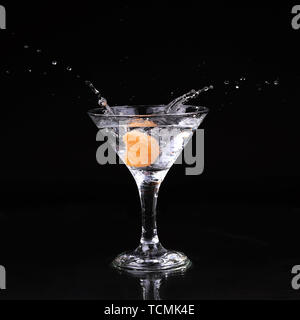 martini cocktail splashing into glass on black background Stock Photo