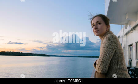Woman admiring landscape from deck of cruise ship after sunset Stock Photo