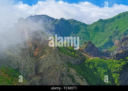 Nature scene of green mountains against cloudy blue sky. View from Pico do Ariero on Portuguese island of Madeira Stock Photo