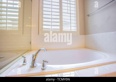 Bathroom interior with built in bathtub and shiny towel rod on the white wall Stock Photo