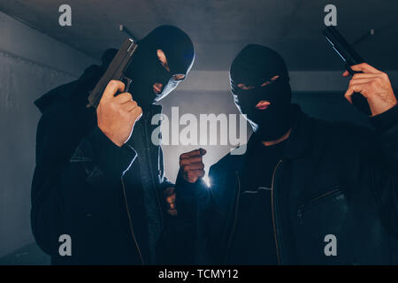 Masked men are holding guns in basement Stock Photo