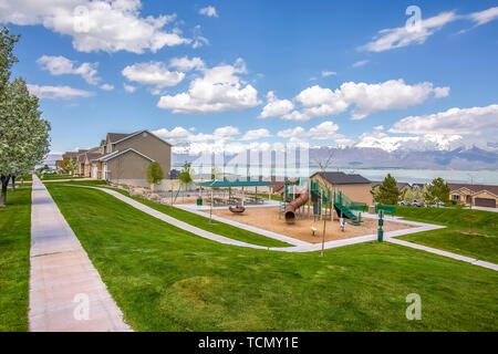 Playground and homes on a residential area with view of lake and snowy mountain Stock Photo