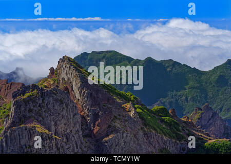 Panoramic view of mountain peaks against clouds below horizon and clear blue sky on sunny day. View from Pico do Arieiro on Portuguese island of Madei Stock Photo