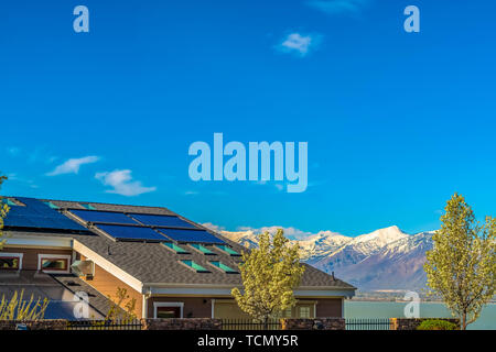 Roof with solar panels and skylights against lake and mountain under blue sky Stock Photo