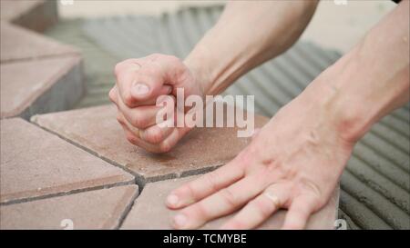 Worker lay tiles on the sidewalk. Laying concrete paving slabs in house courtyard driveway patio. Professional workers bricklayers are installing new Stock Photo