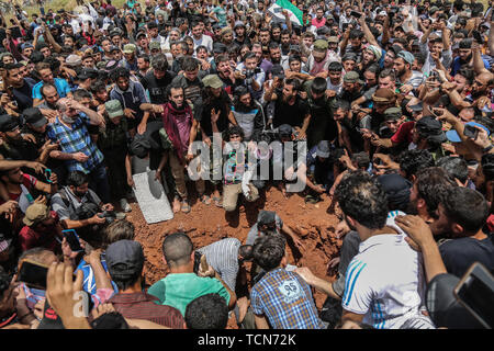 Ad Dana, Syria. 09th June, 2019. People bury the body of Abdel-Baset al-Sarout, a 27-year-old Syrian goalkeeper who joined the armed rebellion against President Bashar al-Assad, during his funeral after he died on Saturday of injuries sustained in fighting against al-Assad·s forces in the countryside of the province of Hama. The ex-goalkeeper of Syria·s junior team was among the first athletes who joined the anti-al-Assad revolt when it erupted in 2011. Credit: Anas Alkharboutli/dpa/Alamy Live News Stock Photo