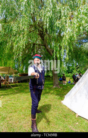 Le Medieval weekend living history event at Sandwich, England. Man, in medieval costume, pointing sword at viewer. Background willow tree. Stock Photo