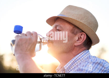 Senior hispanic man in summer hatdrinking fresh water Stock Photo