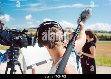 Woman holding microphone on a boom during video production capturing audio Stock Photo