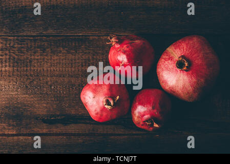 Four ripe pomegranate on rustic wooden table Stock Photo