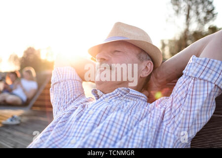 Old hispanic man sits on bench, smiling, enjoying summer sunny day. Stock Photo