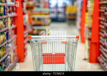 Empty shopping cart with blur supermarket  store aisle and product shelves interior background Stock Photo