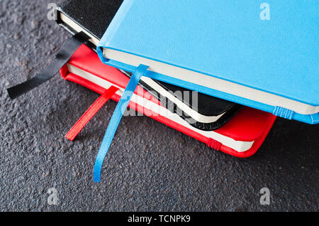 Stack of colorful notebooks for writing or books on dark background. Stock Photo