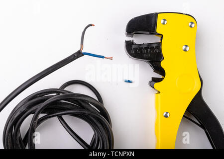 Device for removing insulation from electric cables. Accessories for the electrical installer. Light background. Stock Photo