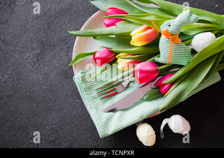 Easter table setting with bouquet of tulips and cutlery. Preparing for the festive Easter dinner. Top view. Stock Photo