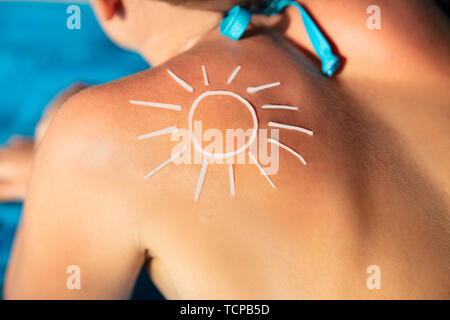 An Overhead View Of Sun Drawn On Woman's Back With Sunscreen Lotion Stock Photo