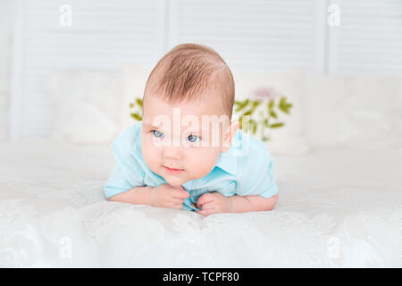 photo of little boy is lying on the bed next to a teddy bear Stock Photo