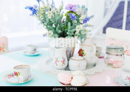 Photo of Flowers, tea set and sweets on the table Stock Photo