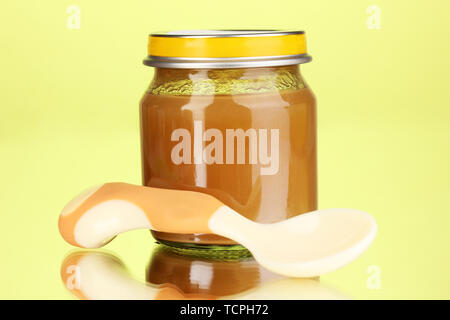 Useful and tasty baby food with beige small spoon on green background Stock Photo