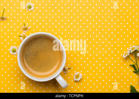 Cup of coffee on a bright yellow background with flowers and a notebook Stock Photo