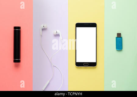 art design concept gadgets. smartphone, power Bank, headphones, flash drive on multi-colored striped background Stock Photo