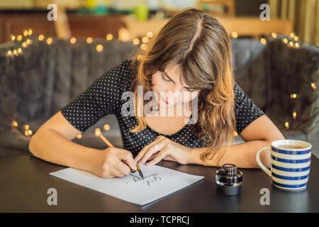 Good morning. Calligrapher Young Woman writes phrase on white paper. Inscribing ornamental decorated letters. Calligraphy, graphic design, lettering Stock Photo