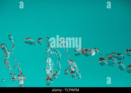 Water droplets frozen in the air with splashes and chain bubbles on a green and turquoise isolated background in nature. Clear and transparent liquid  Stock Photo