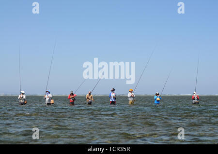 Typical Balinese fishermen standing in a row in the shallow water of Sanur Beach in Bali, Indonesia Stock Photo