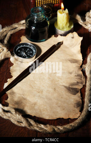 Old paper with ink pen near lighting candle on wooden table Stock Photo
