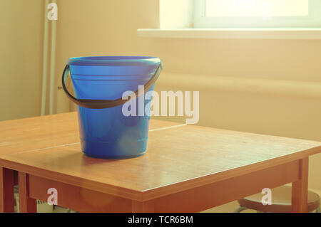 blue bucket on the table at the sunny window before cleaning the room Stock Photo