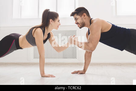 Sporty couple lovingly look at each other and sit ups Stock Photo