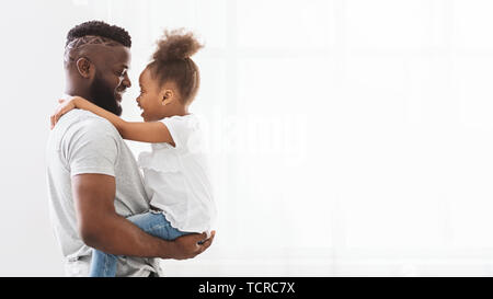 Black man embracing his cute little daughter near window Stock Photo