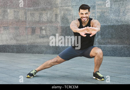 Young muscular man doing stretching exercises outdoor Stock Photo