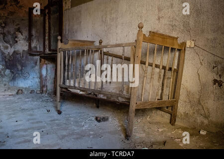 Old cradle abandoned in a empty room. A glimpse of ghost town Alianello. Matera province, Italy Stock Photo