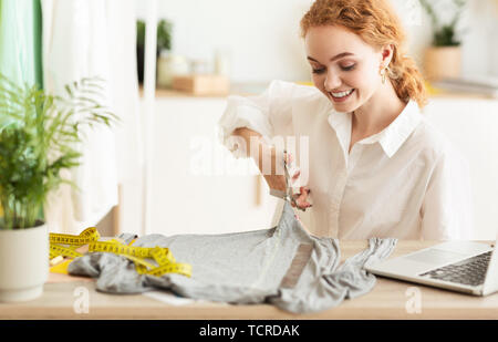 Fashion Designer Cutting Grey Fabric In Workshop Stock Photo