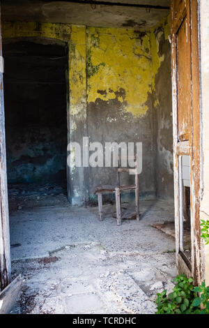 Old chair abandoned in a empty room. A glimpse of ghost town Alianello. Matera province, Italy