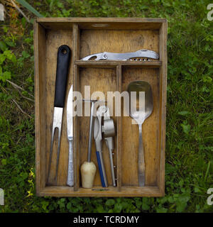Wooden box with various kitchen utensils placed on the ground Stock Photo