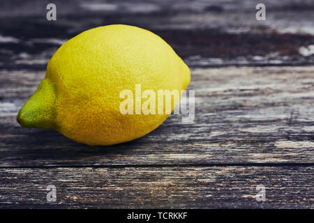 one lemon lying on a wooden background with copy space Stock Photo