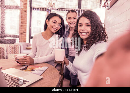 Three beaming women smiling while making photo spending morning in bakery Stock Photo
