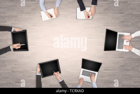 Group of people with devices in hands having desk discussion and making reports together on laptop, tablet, notebook  Stock Photo