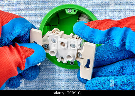 Technician repairing of electrical wiring at home, he fixes loose outlet. Stock Photo