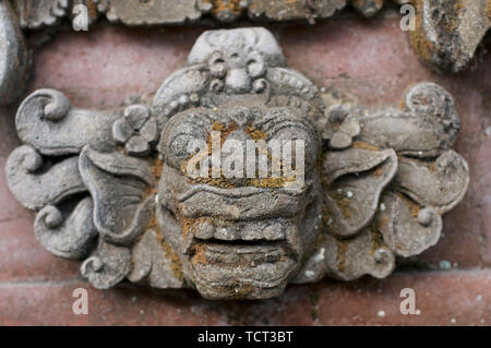 Beautiful stone detail of a Balinese Barong mask captured on a wall in Ubud village in Bali, Indonesia Stock Photo