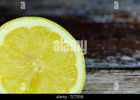 close up of a chopped lemon lying in the corner of a wooden background with copy space Stock Photo