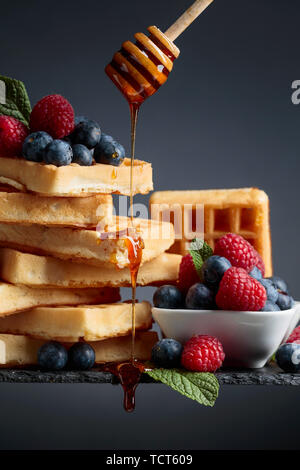 Belgian waffles with  blueberries, raspberries  and honey garnished with fresh mint. Stock Photo