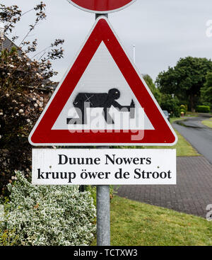 10 June 2019, Schleswig-Holstein, Börms: A homemade warning traffic sign with the pictogram of a person on all fours holding a bottle and the Low German signature 'Duuune Nowers kruup öwer de Stroot', translated as 'Drunken neighbours crawl across the street', stands in the 30 kilometre zone of a residential home. Photo: Markus Scholz/dpa Stock Photo