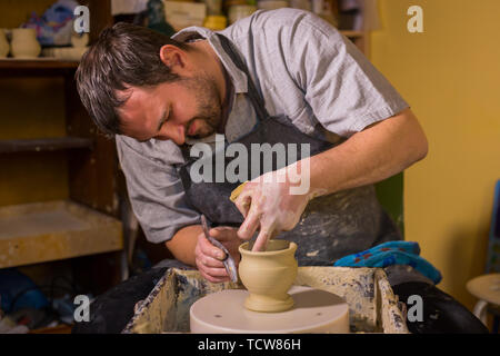 Professional male potter working with clay on potter's wheel Stock Photo